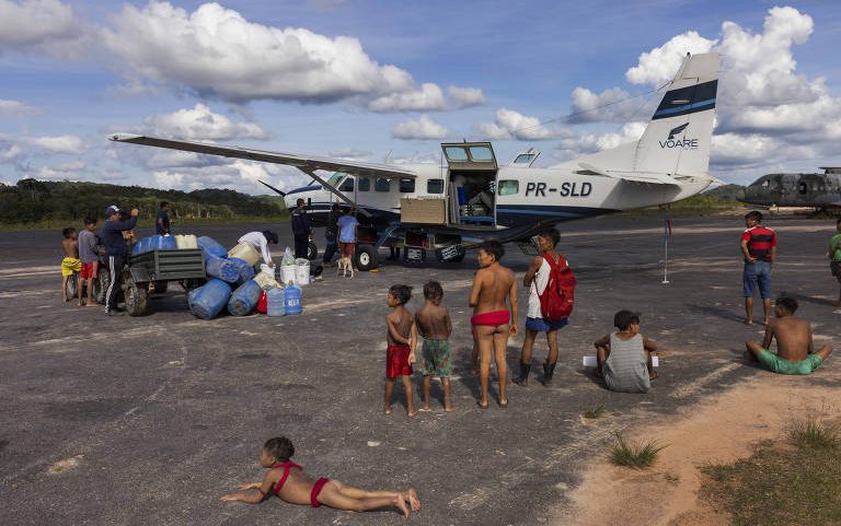 Indígenas observam a movimentação de aeronaves na pista de pouso do polo base de Surucucu, na Terra Indígena Yanomami, em Roraima