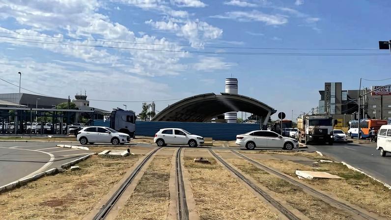 Imagem mostra em primeiro plano trilhos num canteiro central, com carros passando ao fundo