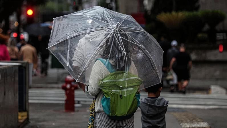 Mulher se protege da chuva na avenida Paulista