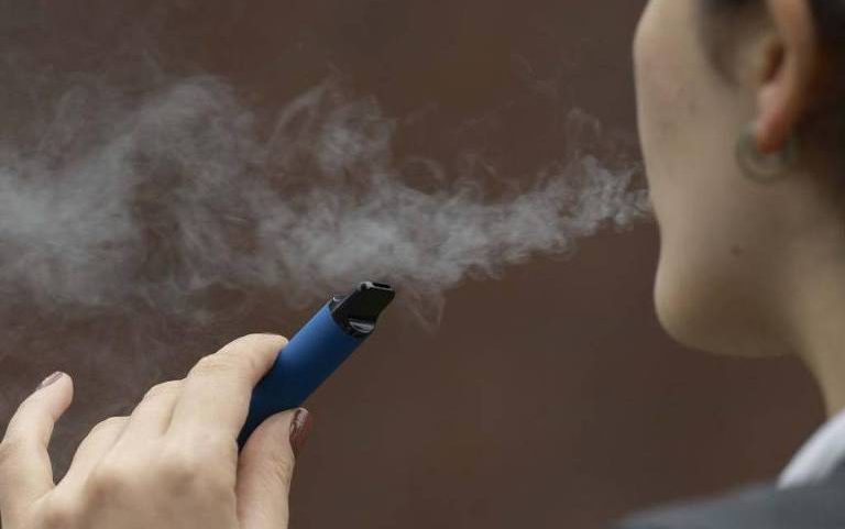 Jovem fuma cigarro eletrônico