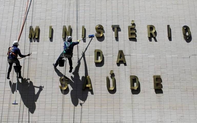 Funcionários limpam fachada do prédio do Ministério da Saúde, em Brasília