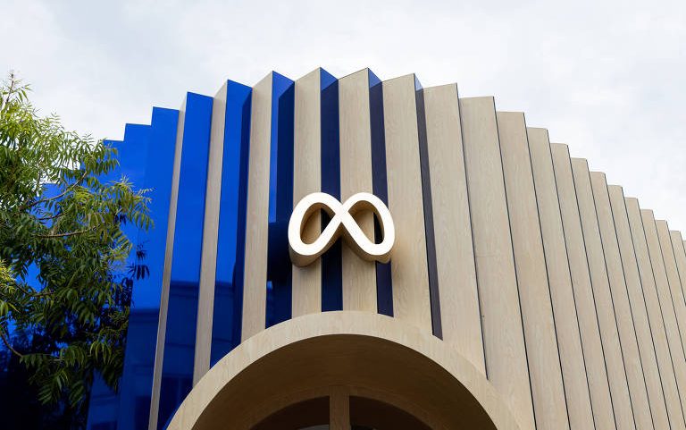 Fachada moderna com painéis verticais em azul e bege, exibindo o logo branco do Meta centralizado acima de arco de entrada.