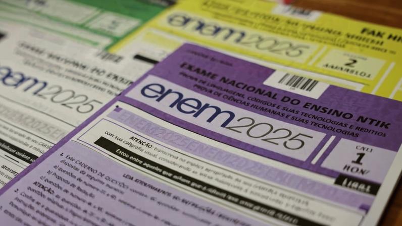 Cartões de inscrição do Exame Nacional do Ensino Médio (ENEM) 2025 dispostos em sequência, com destaque para o cartão roxo em primeiro plano. Cada cartão exibe o logo 'enem 2025' e informações impressas em texto pequeno.