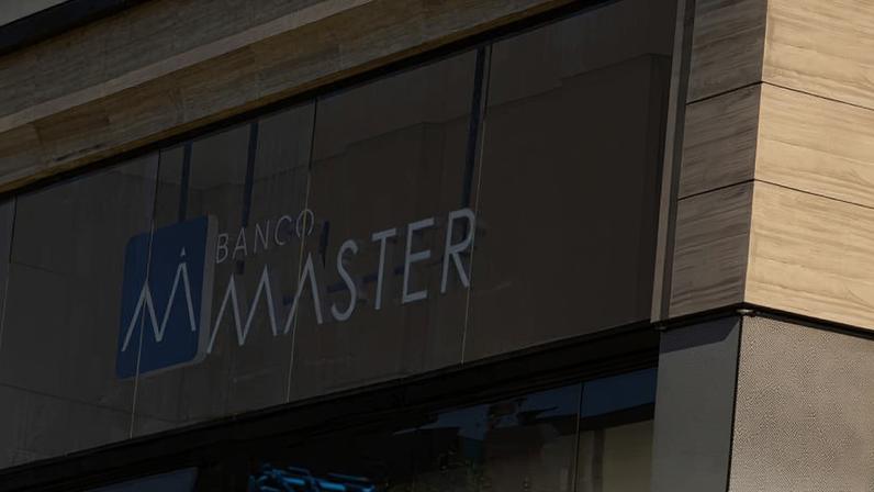 Fachada do banco Master, em São Paulo, próxima a um semáforo com o sinal vermelho