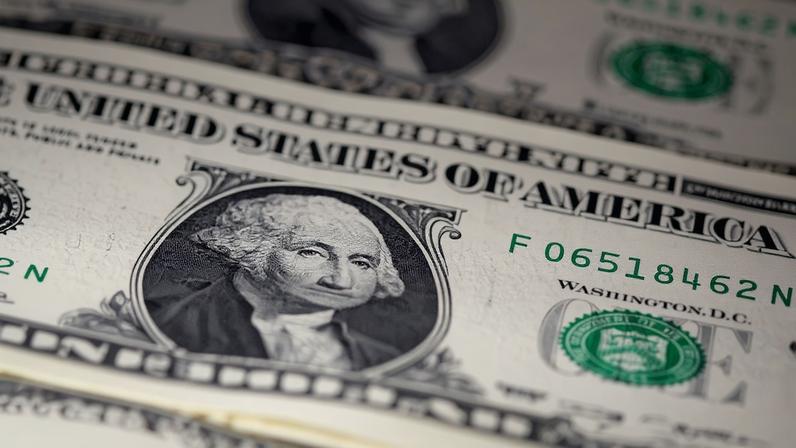 Notas de dólar americano de um dólar dispostas em superfície, com destaque para o retrato de George Washington e o número de série verde visível.