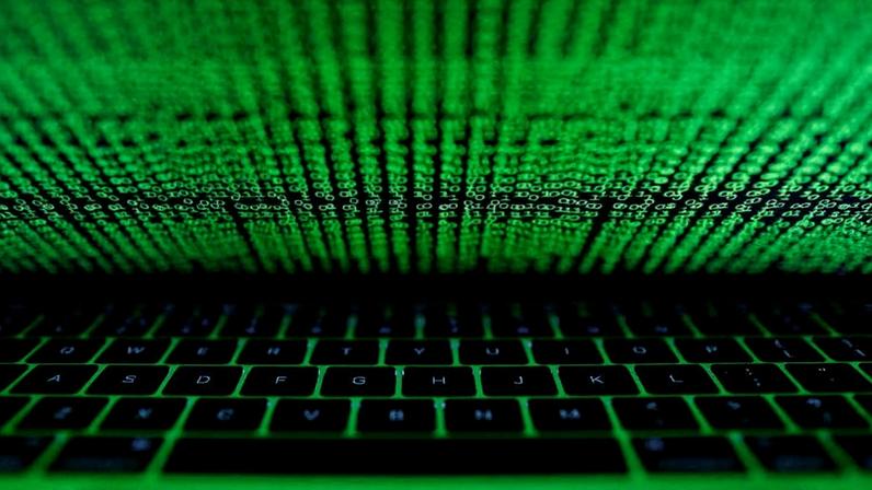 Luz de tela de computador com códigos refletida em teclado