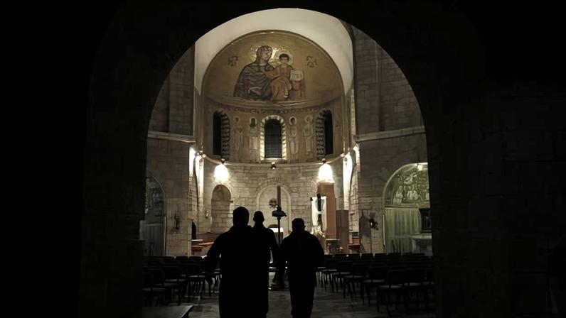 Um padre e um policial israelense caminham em santuário católico no monte Sião, em Jerusalém