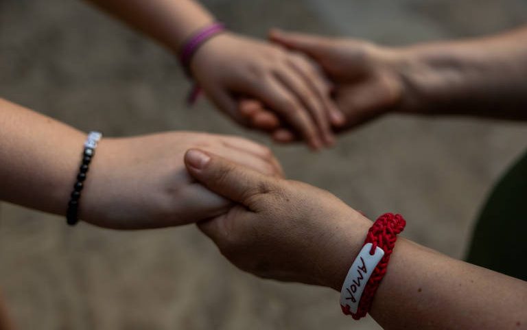 Mãe e filha de mãos dadas em instituição que oferece assistência a mulheres e crianças