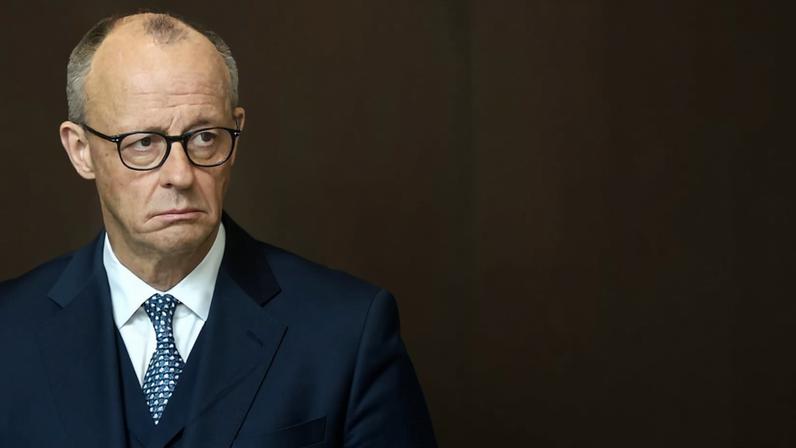 Friedrich Merz, fotografado atrás de uma janela de vidro que reflete a imagem de soldados de guarda de honra, aguarda a chegada do primeiro-ministro da Holanda, Rob Jetten, para visita oficial em Berlim, em março