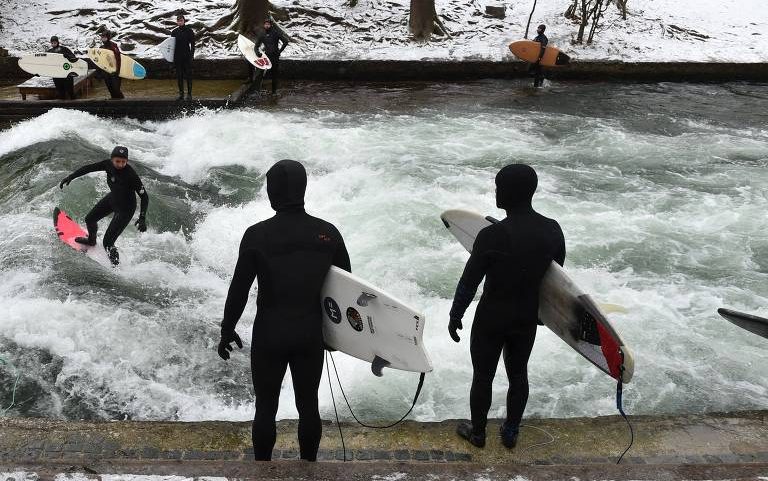 Surfista desliza sobre uma onda no canal do rio Eisbach, em Munique