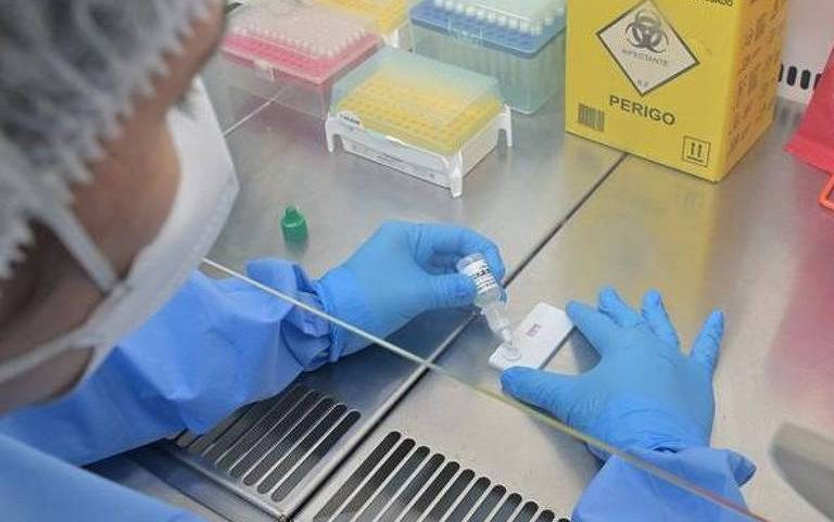 Mulher usa equipamentos de proteção para realizar teste em um laboratório