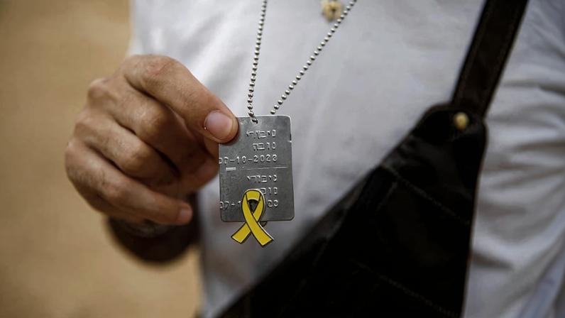 Sobrevivente do ataque de 7 de Outubro segura uma placa de identificação com as palavras em hebraico “Heróis do Nova", em referência ao festival de música alvo dos terroristas