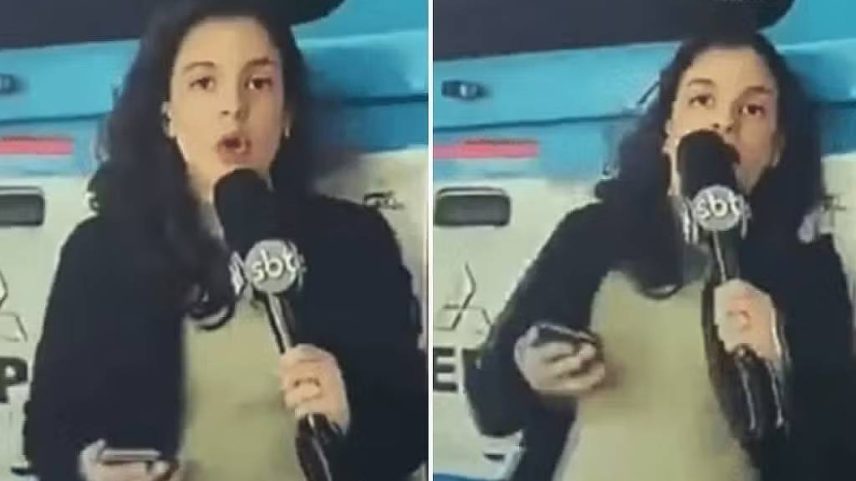Repórter segura microfone com logo do SBT e celular, em frente a viatura policial azul e branca. Ela veste casaco preto e blusa clara, com cabelo solto.