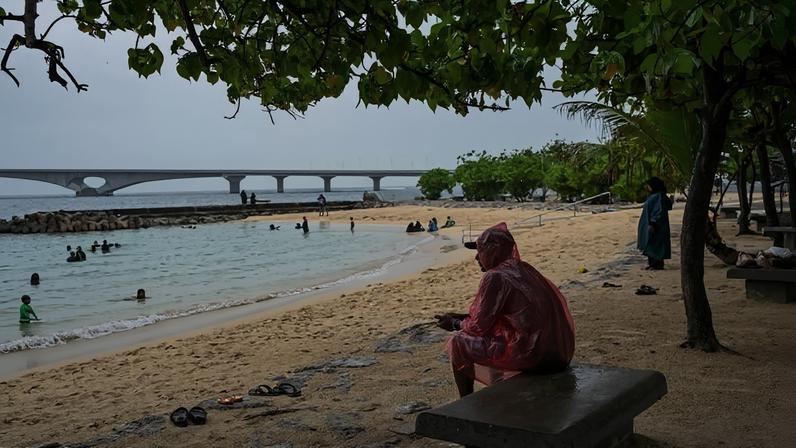Homem senta sob árvore em praia de Malé, nas Maldivas