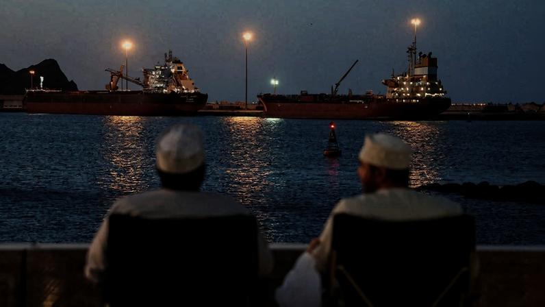 Moradores em Omã observam navios atracados no porto de Muscat
