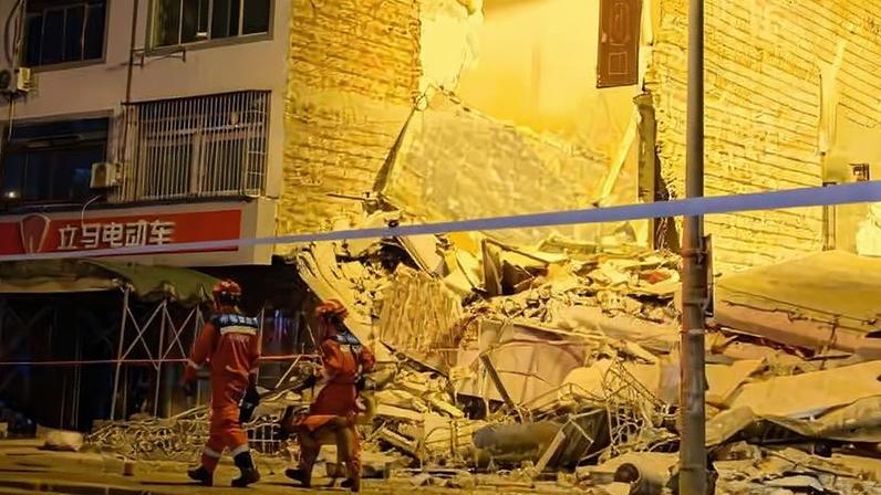 Socorristas caminham ao lado de um prédio desabado após um terremoto em Liuzhou, na região de Guangxi, no sul da China