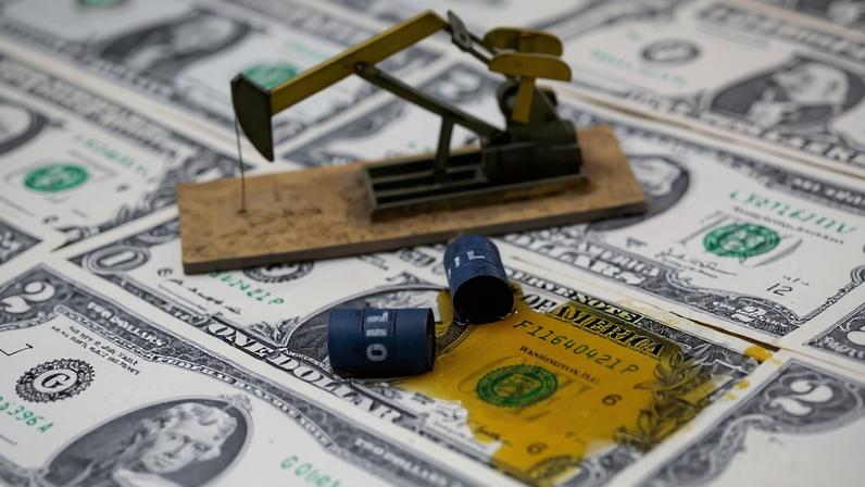 Notas de dólares com líquido que simula petróleo derrubado de miniatura de barris
