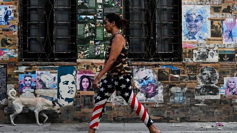 Mulher usando leggings com a bandeira dos Estados Unidos em frente a pôster do ex-presidente cubano Raúl Castro e de Ernesto "Che" Guevara, em Havana, em 19 de maio de 2026 - Yamil Lage/AFP