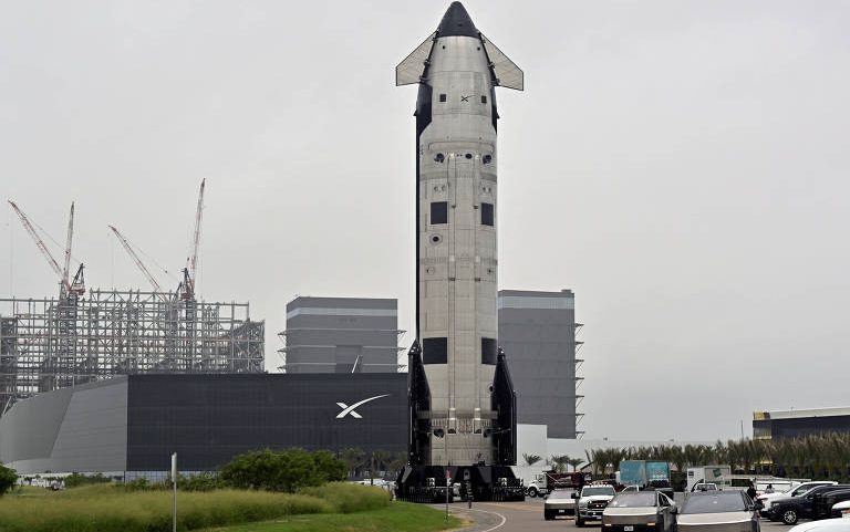 Foguete Starship em frente a uma unidade de produção da SpaceX