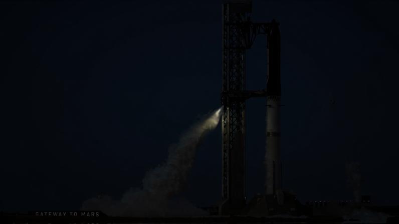 Foguete Falcon 9 da SpaceX na plataforma de lançamento com vapor saindo da base. Céu claro e vegetação ao redor da área de lançamento.
