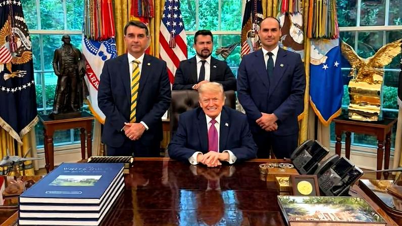 Flávio Bolsonaro, o influenciador Paulo Figueiredo e Eduardo Bolsonaro com Donald Trump em encontro na Casa Branca, nesta terça-feira (26)