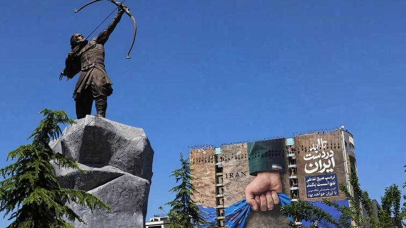 Estátua da figura lendária de Araxe, o Arqueiro, é vista na Praça de Vanak em Teerã, no Irã, com cartaz comemorando o bloqueio de Hormuz ao fundo