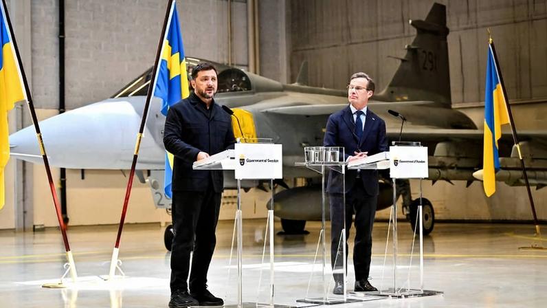 Com um Gripen ao fundo, Zelenski e o premiê sueco, Ulf Kristersson, falam com a imprensa em Uppsala