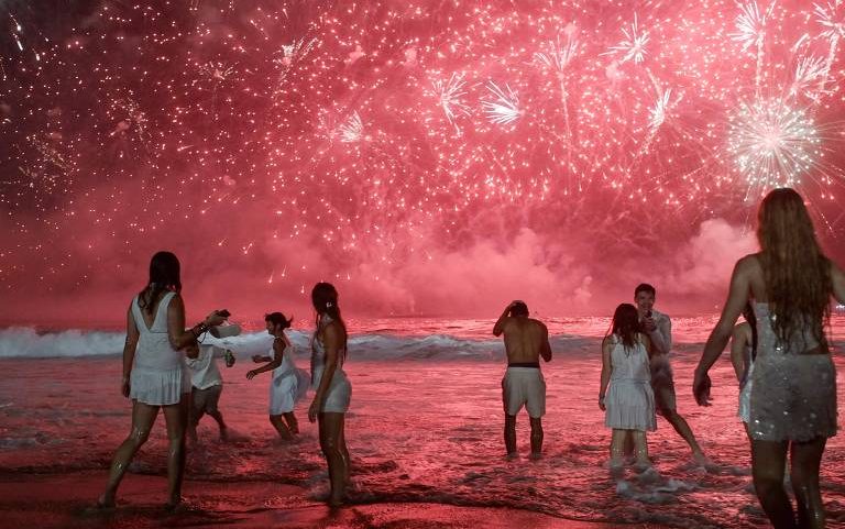 Pessoas assistem à queima de fogos no Réveillon na praia de Copacabana (RJ)
