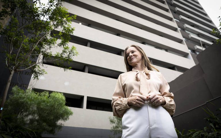 A investidora Carla Tümmler diante de prédio feito exclusivamente para locações para curta permanência