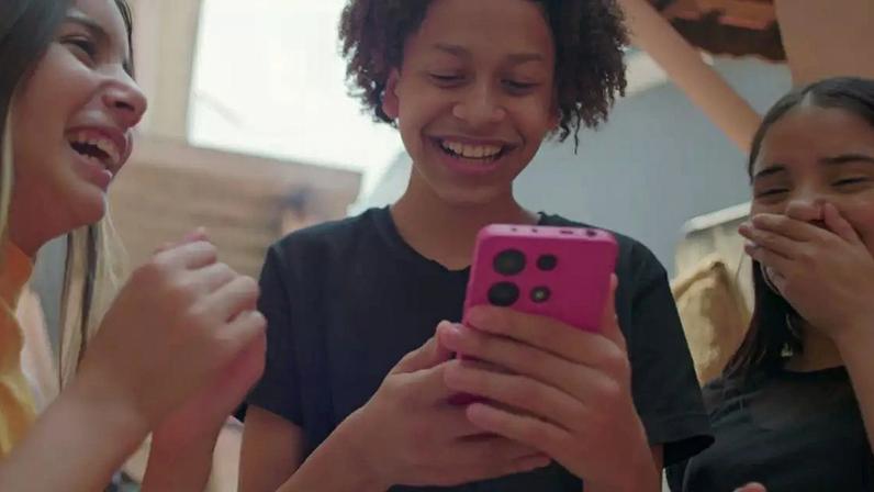 Adolescentes rindo enquanto olham para o celular.