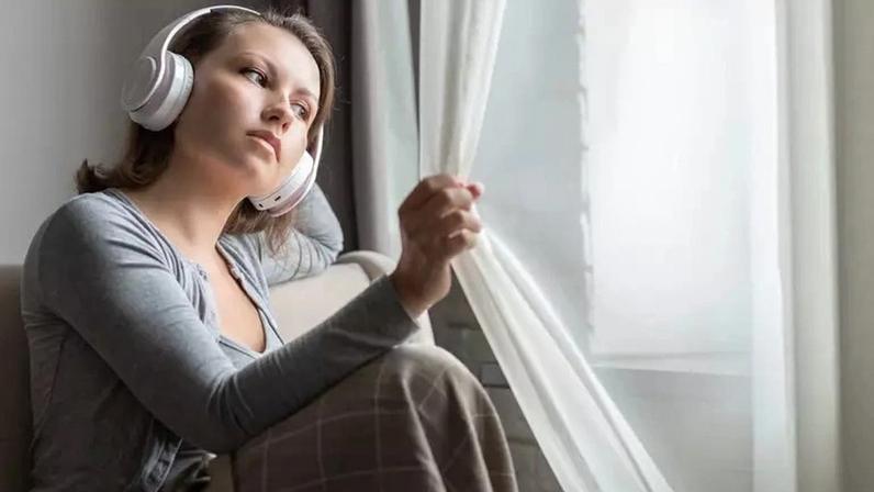 Mulher com semblante triste ouve música nos fones de ouvido