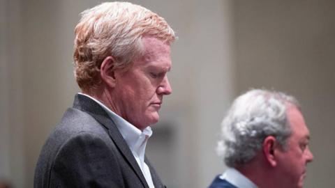 The State/Getty Images Alex Murdaugh wears a grey suit and a white shirt. He looks down as he hears his guilty verdicts in the trial over his wife and son's death.