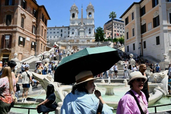 Na Praça da Espanha, em Roma, turistas tentam se proteger do calor de 32°C registrado ontem: clima é incomum para maio, e governo italiano decretou alerta vermelho