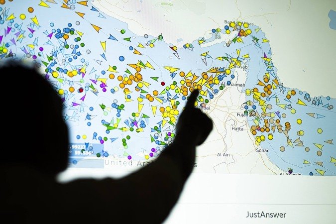 Uma foto ilustrativa tirada em Nicósia em 4 de maio de 2026 mostra uma pessoa em frente a uma grande tela exibindo os movimentos de embarcações no Estreito de Ormuz em um site de rastreamento de navios - (crédito: AFP)