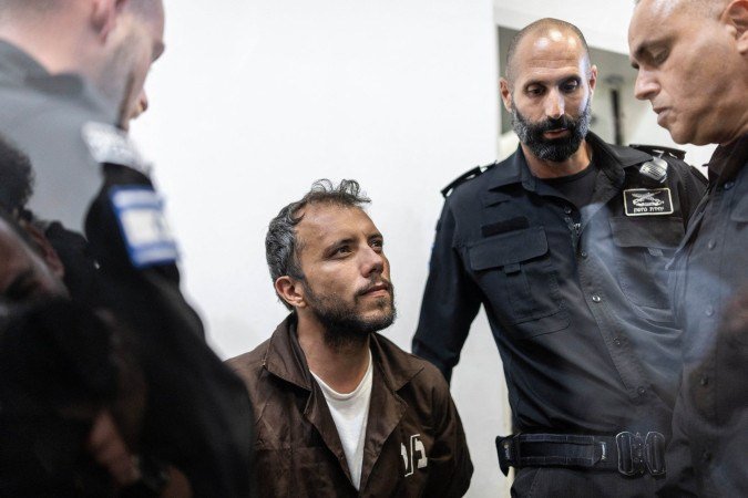O ativista brasileiro Thiago Ávila é escoltado para o tribunal na cidade costeira israelense de Ashkelon, em 5 de maio de 2026 - (crédito: ILIA YEFIMOVICH / AFP)