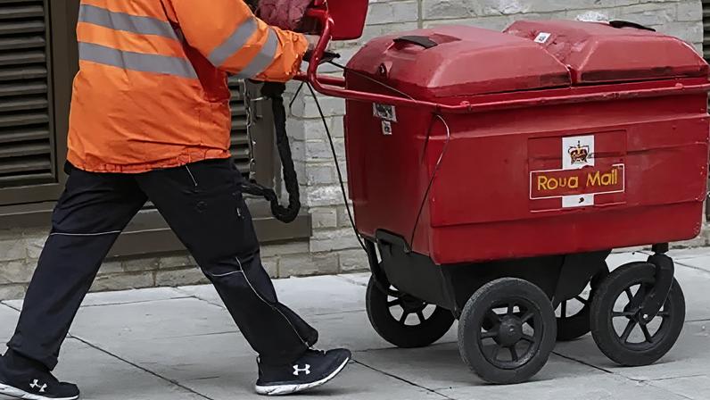 Getty Images A postal worker in a high-vis orange jacket delivering post by pushing a red box, labelled Royal Mail, down a street