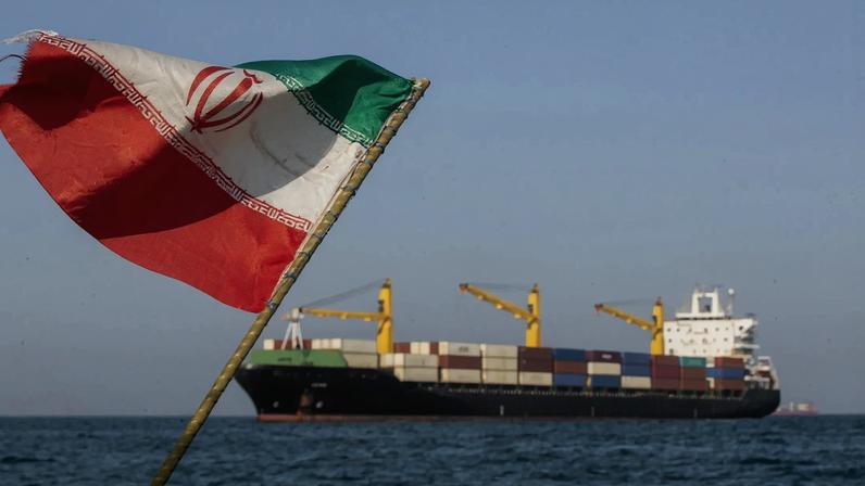 An Iranian flag flutters in the wind as ships remain anchored in the Strait of Hormuz near Larak Island, Iran, on May 16.