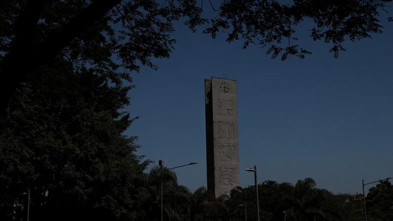 Foto mostra paisagem com árvores e, ao centro, a Torre do Relógio, na Praça do Relógio do campus Butantã da Universidade de São Paulo