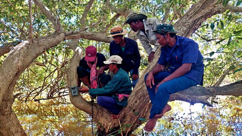 A local guide training Community-Based Fire Management (CBFiM) members with camera trap set up.
