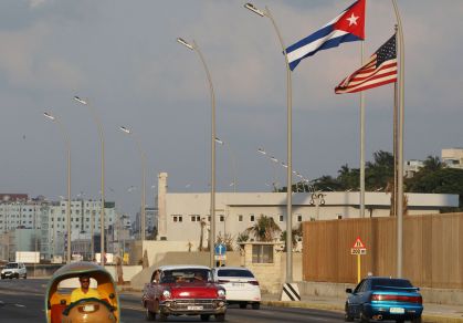 Carros passam por bandeiras cubana e americana ao lado da Embaixada dos EUA em Havana, Cuba
