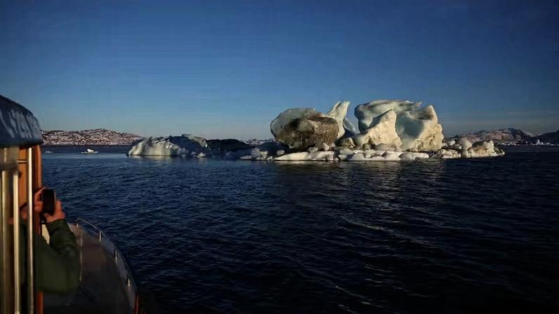 Isak Brandt, que dirige uma empresa de passeios turísticos de barco no Ártico , fotografa um bloco de gelo flutuante enquanto pilota uma embarcação perto de Nuuk, na Groenlândia, em 30 de janeiro de 2026.