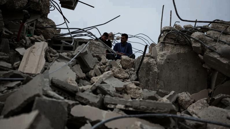 Homens palestinos sentam-se em meio aos escombros de um prédio demolido pelo exército israelense , na cidade de Shuqba, perto de Ramallah, na Cisjordânia ocupada por Israel , em 9 de fevereiro de 2026