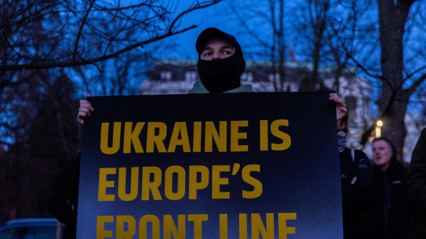 Um homem segura um cartaz durante um concerto chamado 'Ruído pela Ucrânia ' em frente à Embaixada da Rússia, para marcar o quarto aniversário da invasão da Ucrânia pela Rússia , em Praga, República Tcheca, 24 de fevereiro de 2026. Organizado pelo festival United Islands, o evento visa demonstrar solidariedade à Ucrânia e contou com o apoio de diversas embaixadas.