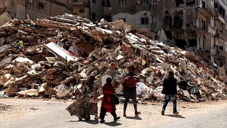 Pessoas caminham sobre os escombros de um prédio destruído por um ataque israelense, em meio à escalada das hostilidades entre Israel e o Hezbollah, enquanto o conflito entre EUA e Israel com o Irã continua, em Tiro, Líbano