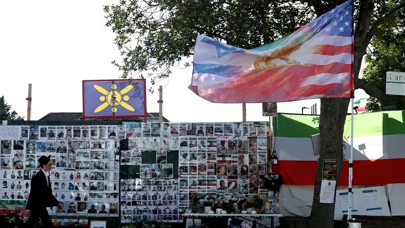 Um membro da comunidade judaica caminha ao lado de um muro memorial dedicado às vítimas dos ataques de 7 de outubro em Israel e aos iranianos mortos em protestos recentes no Irã, na Limes Avenue, em Golders Green