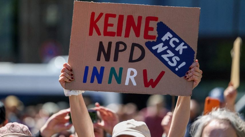 Uma pessoa segura um cartaz enquanto membros das coalizões “Essen stellt sich quer” (ESSQ – “Essen se levanta contra”) e “Omas gegen Rechts” (“Avós contra a direita”) protestam contra uma marcha do partido de extrema direita Die Heimat durante o Dia do Trabalhador, em Essen, Alemanha, 1º de maio de 2026 — Foto: REUTERS/Leon Kuegeler