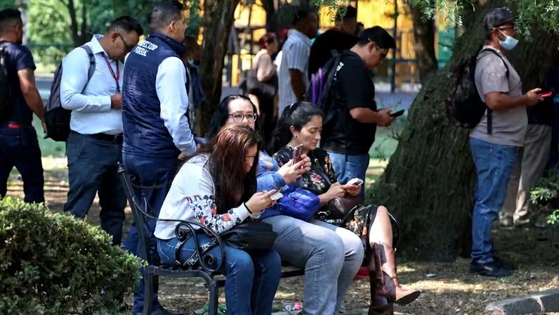Pessoas sentam-se em um banco enquanto esperam do lado de fora, após o alarme de terremoto ter soado, alertando para um tremor, na Cidade do México