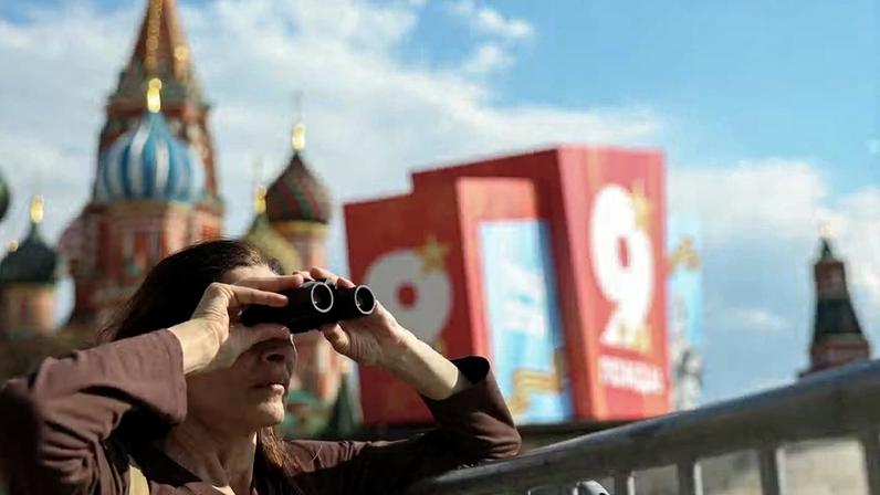 Turista na Praça Vermelha, em Moscou, no dia 4 de maio; ao fundo se vê cartazes celebrando o 9 de maio