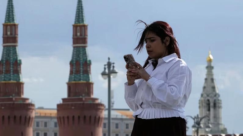Uma mulher consulta seu celular perto do muro do Kremlin, no centro de Moscou