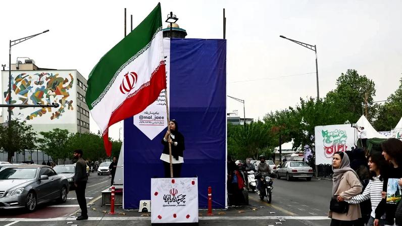 Mulher segura uma bandeira iraniana em uma rua, em meio a um cessar-fogo entre os EUA e o Irã, em Teerã, Irã, 20 de abril de 2026